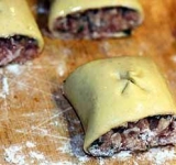 Заготовку разрезаем на кусочки длиной 4-5 см. Сверху рулеты смазываем взбитым яйцом и ножницами прорезаем крестообразный разрез.	