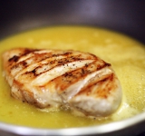 На сковородку с соком выкладываем курицу. В сок вмешиваем ликер с крахмалом. На среднем огне тушим курицу в соусе по три минуты на каждой стороне.	