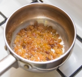 В небольшую кастрюльку добавьте изюм с вином и поставьте на слабый огонь до испарения жидкости.	