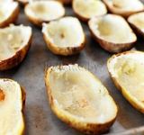 Половинки картофеля выкладываем вновь на противень, посыпаем солью.