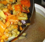 Нарежьте баклажаны на крупные кубики. Нарежьте кубиками перец. Морковку натрите на терке, а лук нарежьте. Разогрейте сковородку с растительным маслом и обжарьте лук с морковкой до золотистого цвета, добавьте баклажан и перец и жарьте еще минут 5-7. Посыпьте любимыми специями, перемешайте и добавьте в суп. Пропустите чеснок через пресс и добавьте его в суп (можно нарезать, а можно и целиком). 
 
Из теста скатайте шарики и по одному опускайте их в бульон. Томите их минт 10. Готовый суп подавайте, посыпав зеленью. Приятного аппетита!	